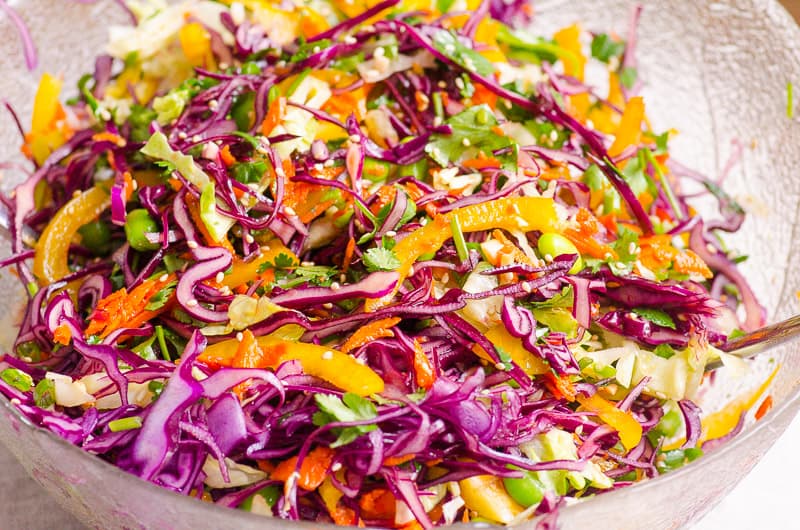 Slaw in a bowl with asian salad dressing and sesame seeds.