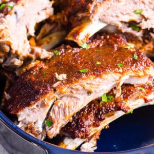 Instant pot ribs recipe with barbecue sauce and parsley in a baking dish.