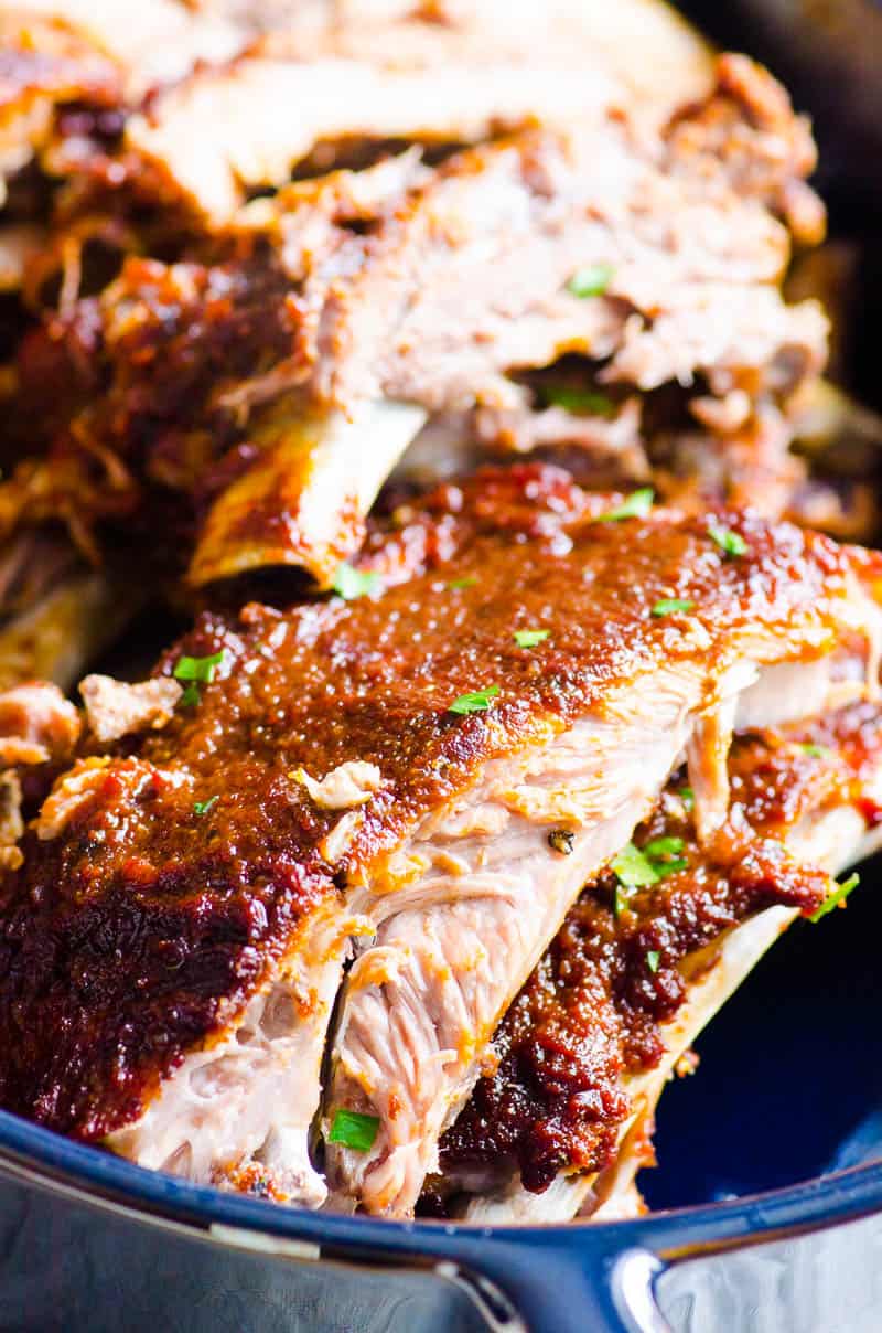 Instant pot ribs recipe with barbecue sauce and parsley in a baking dish.