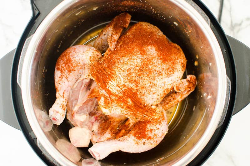 Instant Pot Whole Chicken seasoned on a trivet inside Instant Pot