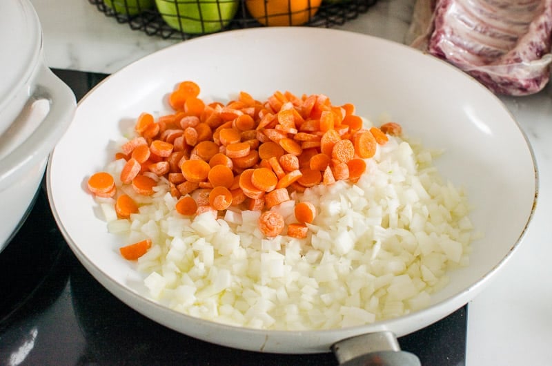 chopped onion and carrots in white skillet