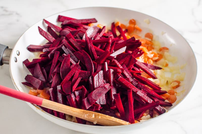 sliced beets and chopped onion and carrots in a skillet