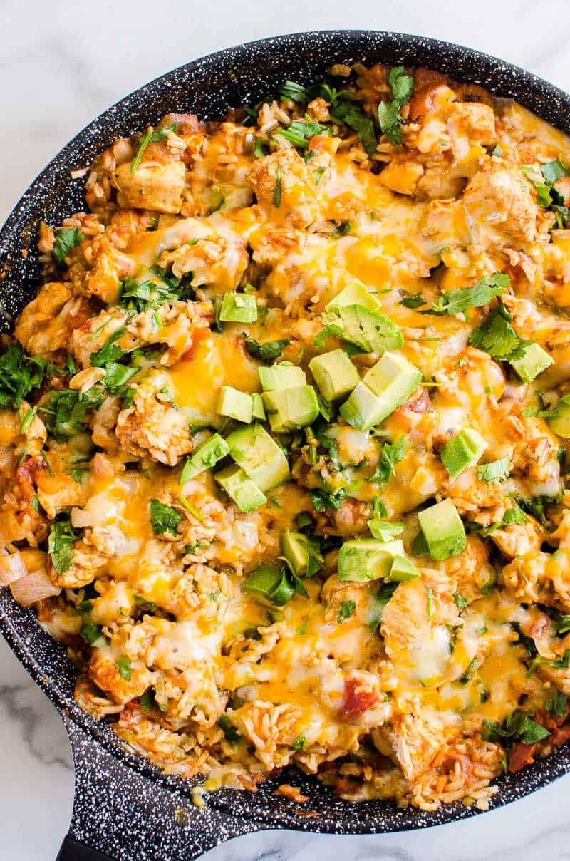 One Pan Mexican chicken and rice garnished with avocado and cilantro.