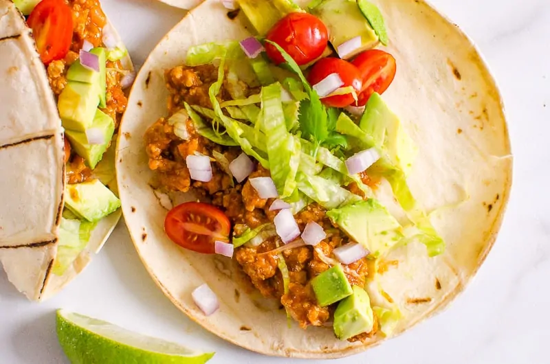 turkey tacos topped with chopped lettuce, tomatoes, avocados