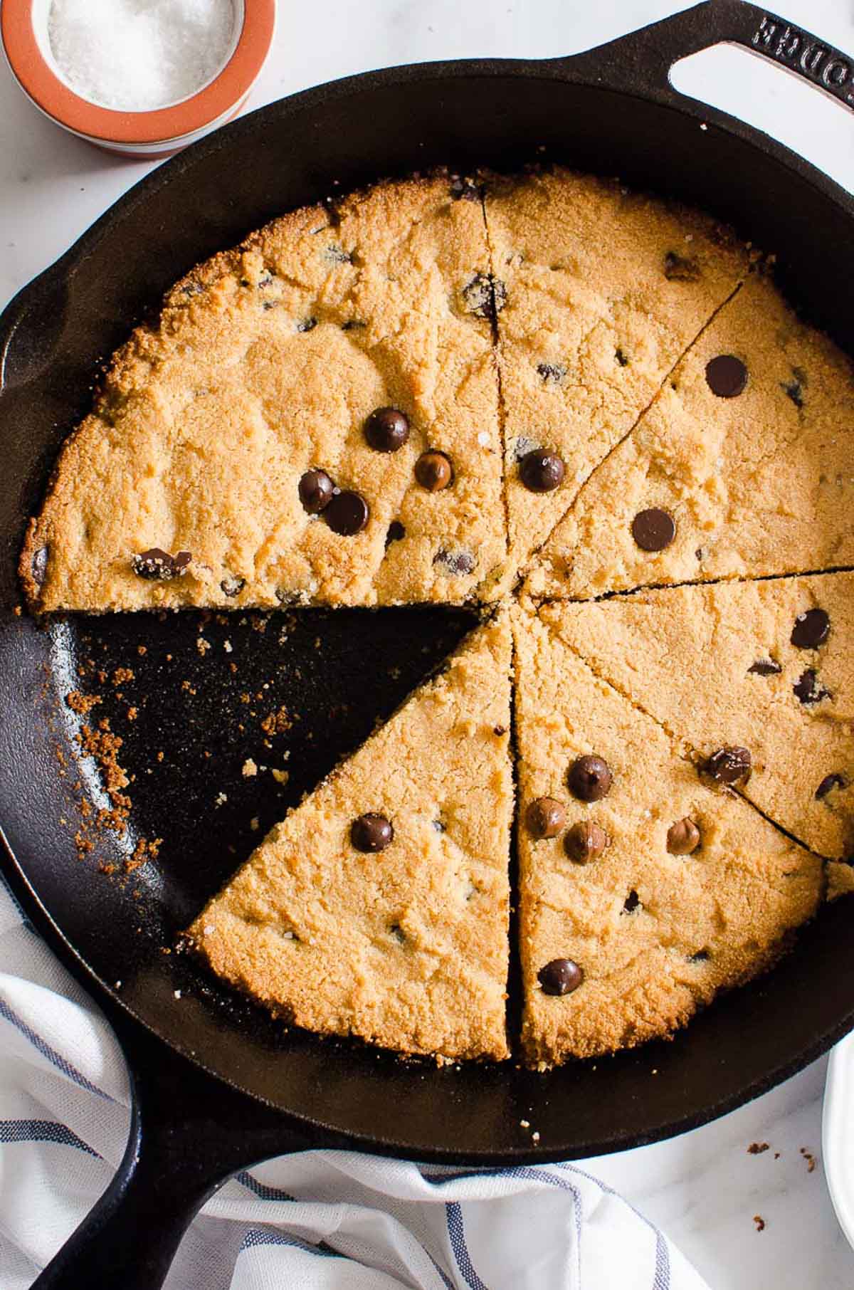Sliced healthy skillet cookie with chocolate chips in a cast iron skillet.