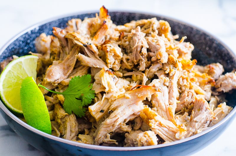 Instant Pot pork carnitas in a bowl with cilantro and lime.