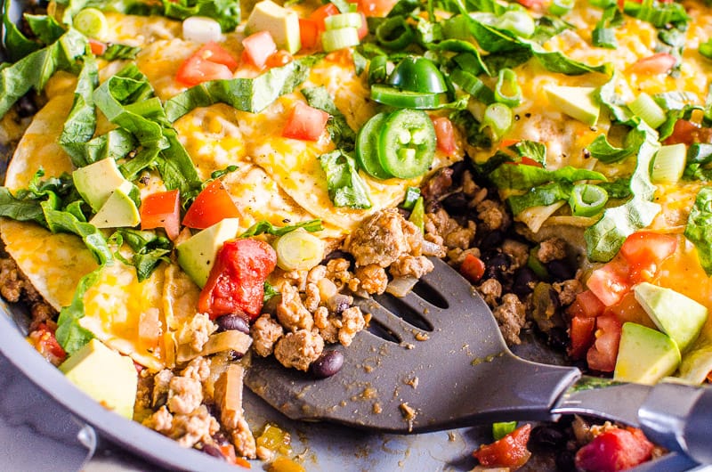 Taco Skillet scooped up with spatula and garnished with traditional taco fixings