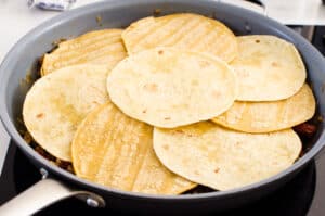 Tortillas in skillet covering food.
