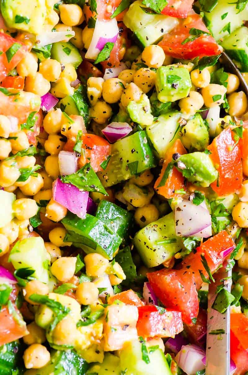 Close up of chickpea avocado salad with red onion, tomatoes and cucumber.