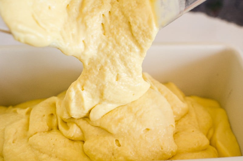 creamy mango ice cream being put in a pan for freezer