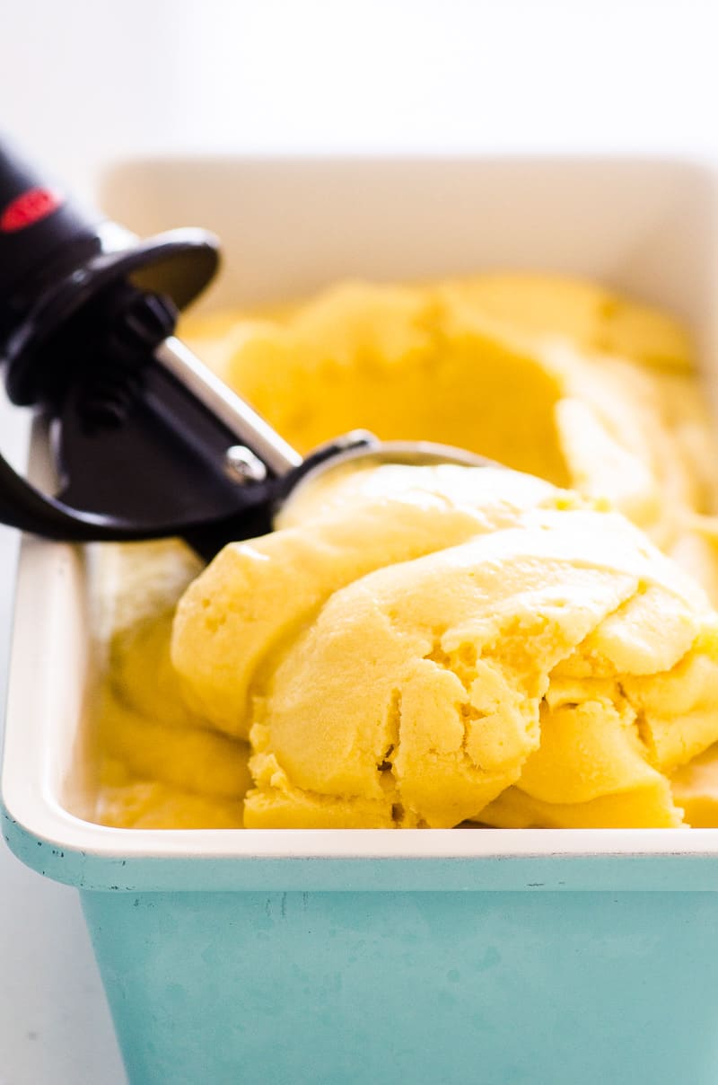 mango ice cream recipe in a blue dish with a scoop