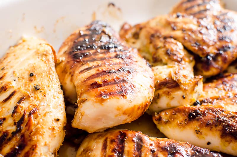 A close up of a plate of food with grilled chicken breasts.
