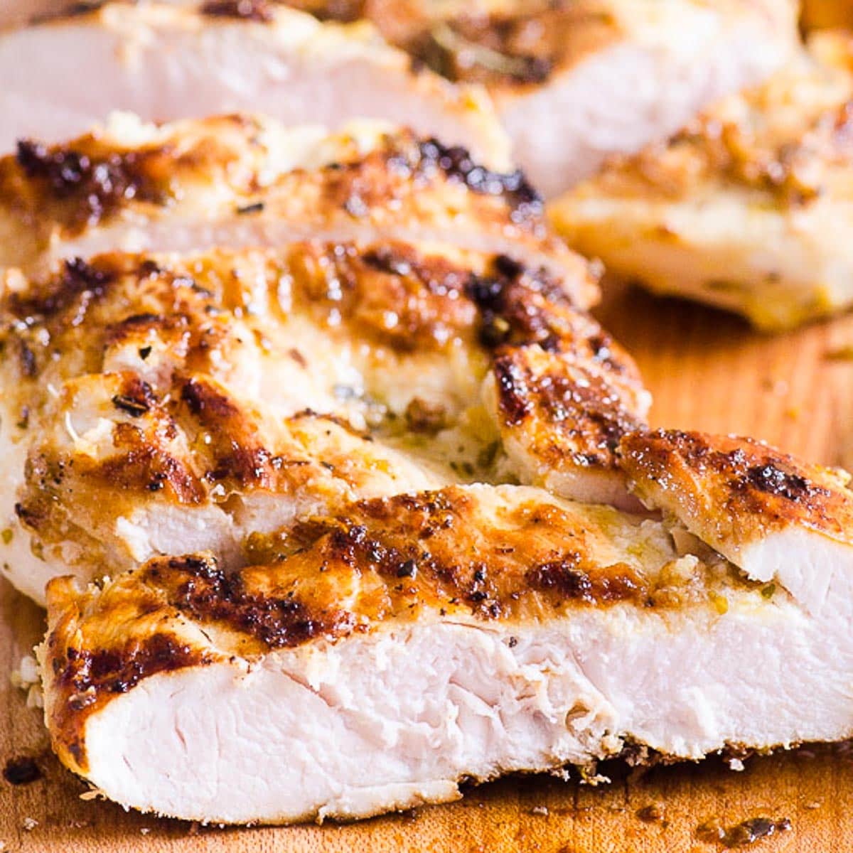 Sliced grilled chicken breast on cutting board.