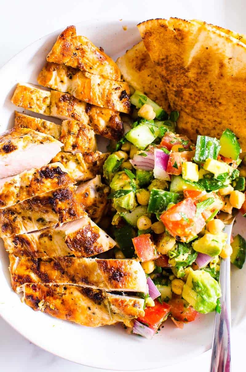 Grilled Chicken Breast with chickpea salad and pita bread served in a bowl with a fork