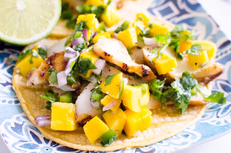 Grilled Fish Tacos with mango salsa on corn tortilla on blue plate