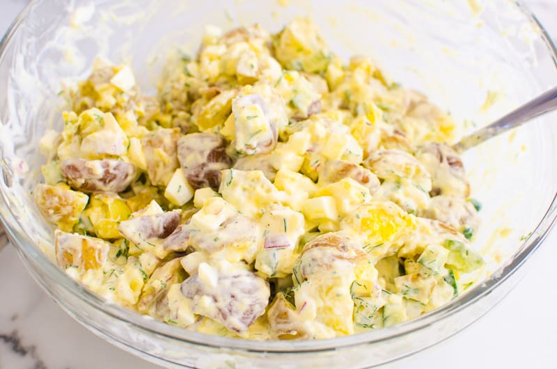 Healthy potato salad served in a glass bowl with a spoon.