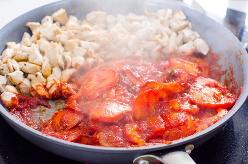 Tomatoes and chicken in skillet.