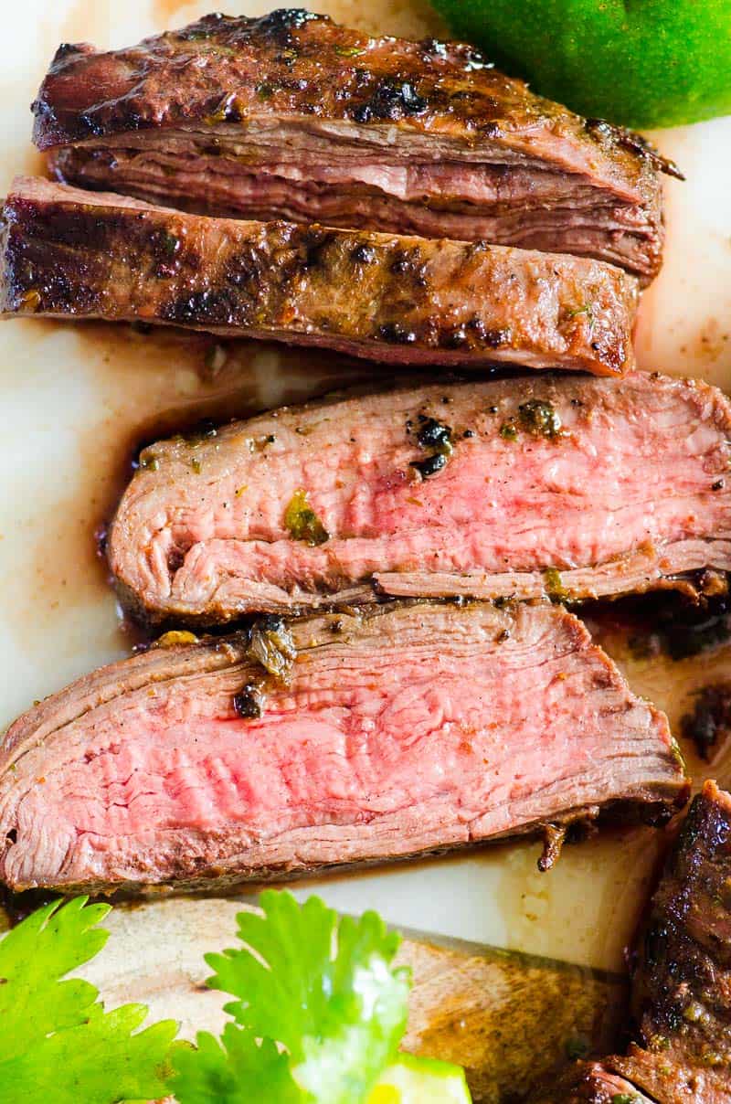 Carne asada steak sliced on a cutting board with cilantro.