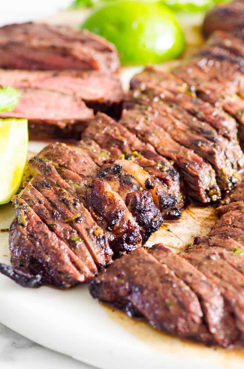 Sliced carne asada steak with lime slices.