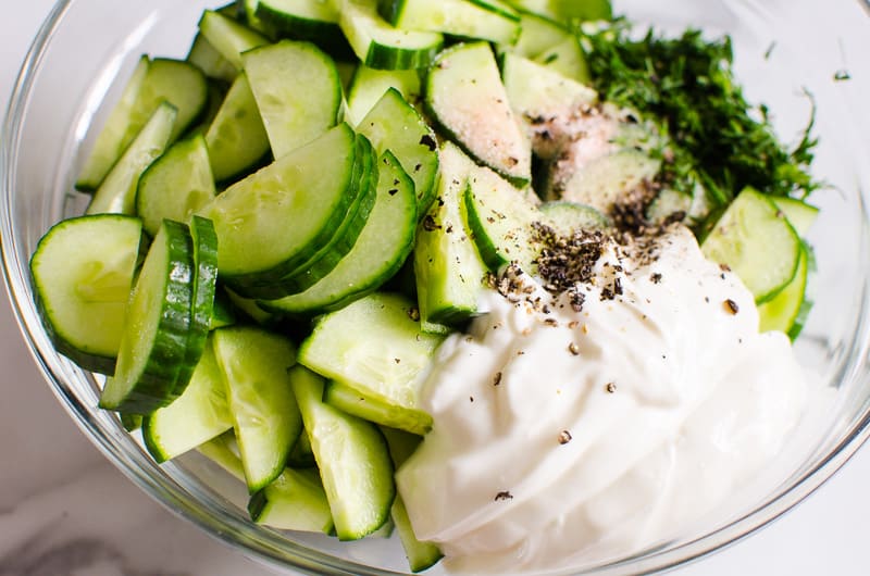 mixing cucumber salad with yogurt and herbs