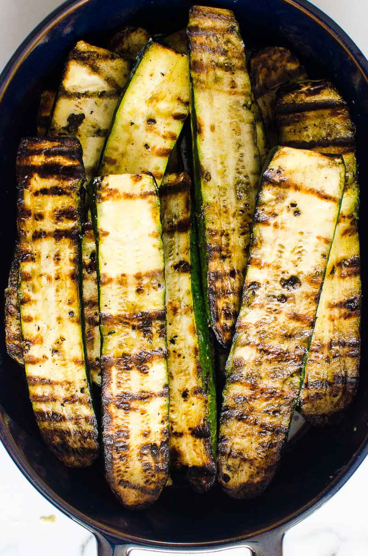 Grilled zucchini planks on top of each other in a dish.