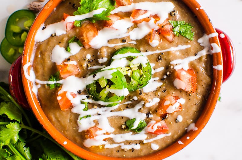 Instant Pot Refried Beans in red bowl with cilantro and jalapenos.