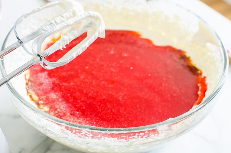 Strawberry puree and beaten cream cheese in a bowl.