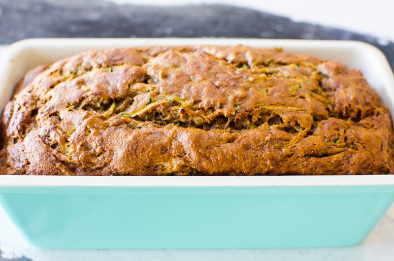 Healthy zucchini banana bread in a blue loaf pan on a countertop.