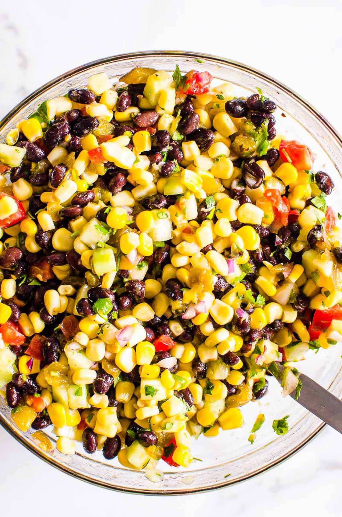 Black bean salsa in a bowl with a serving spoon.