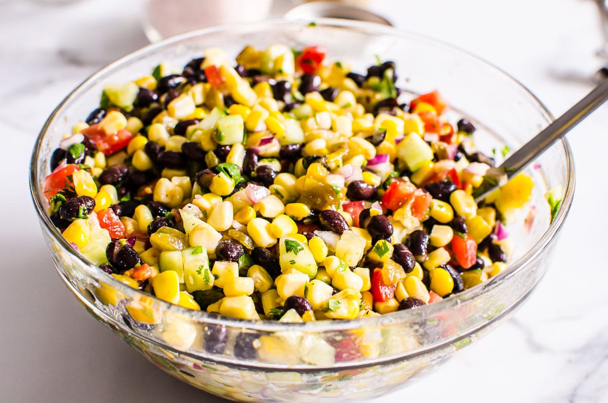 Black bean salsa in a glass bowl with wooden spoon.