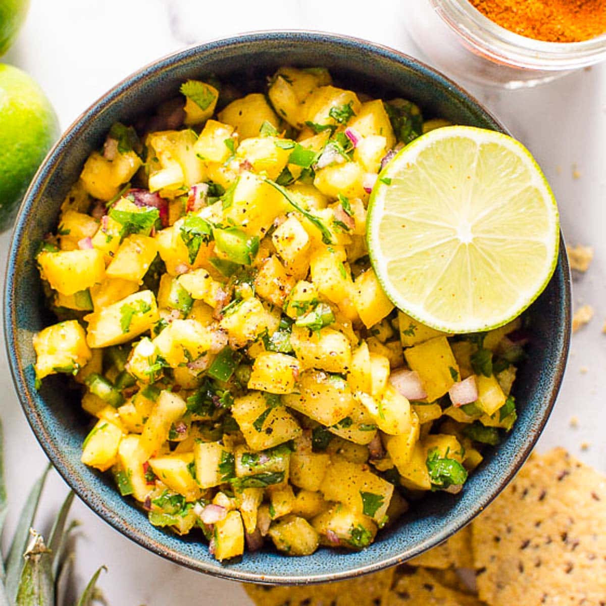 Pineapple jalapeno salsa ina. bowl with lime garnish and chips.