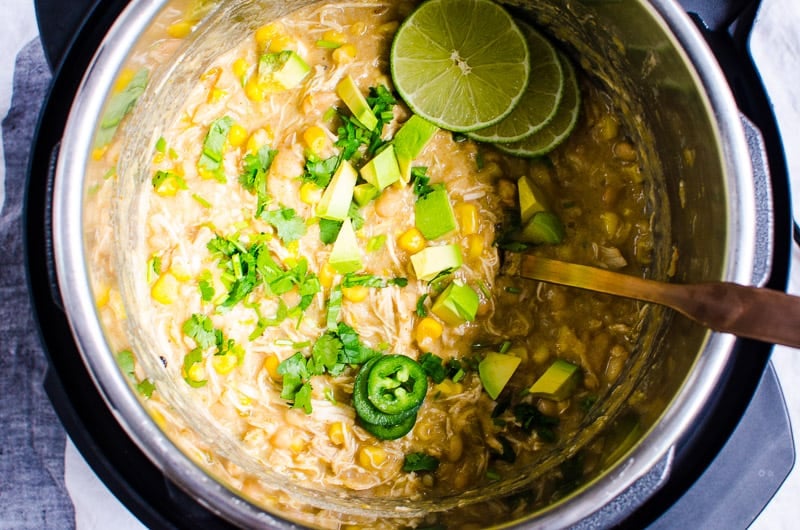 Instant Pot White Chicken Chili garnished with avocado, jalapeno, limes and cilantro