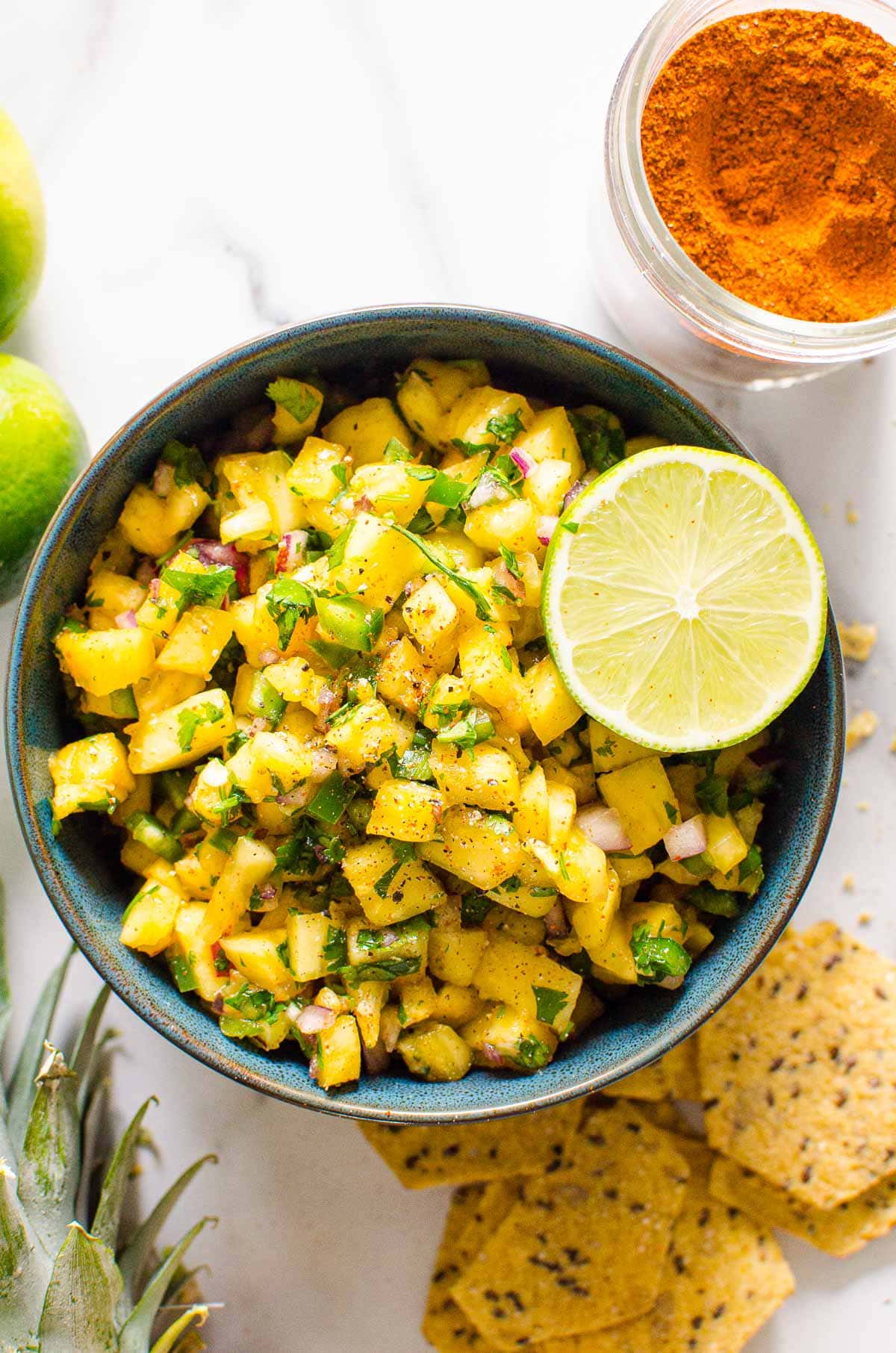 Pineapple jalapeno salsa in a bowl garnished with lime and chips.