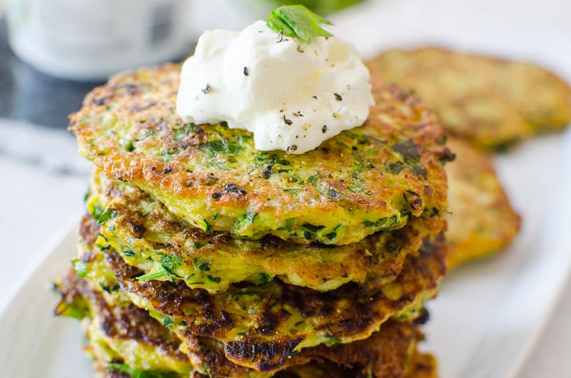 stack of zucchini fritters with two single patties behind stack