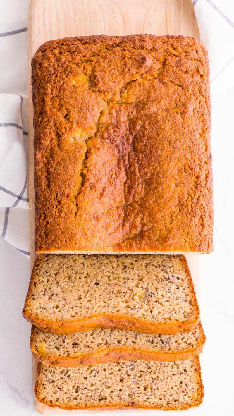 Banana bread with almond flour sliced on a cutting board and linen towel under.