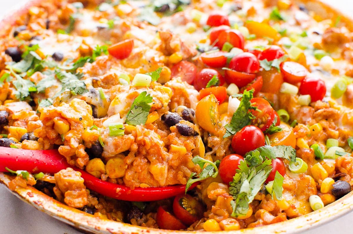 Chicken burrito skillet scooped with red spoon.