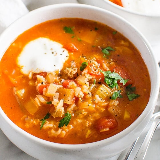Instant Pot stuffed pepper soup in a white bowl with dollop of yogurt.