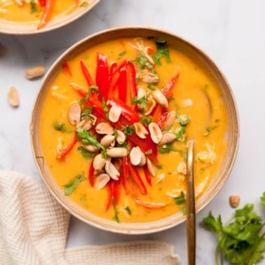 Thai chicken butternut squash with red pepper, peanuts and cilantro in a bowl.