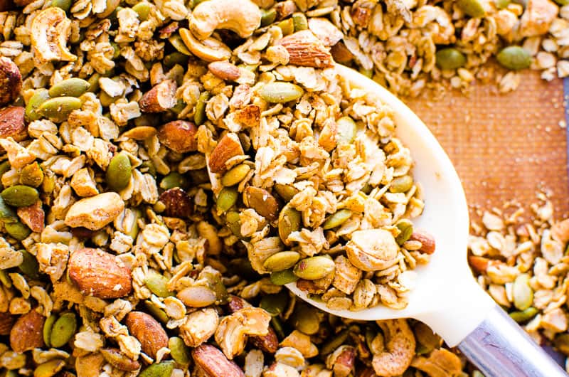 Close up of oats, nuts and seeds on pan with spoon. 