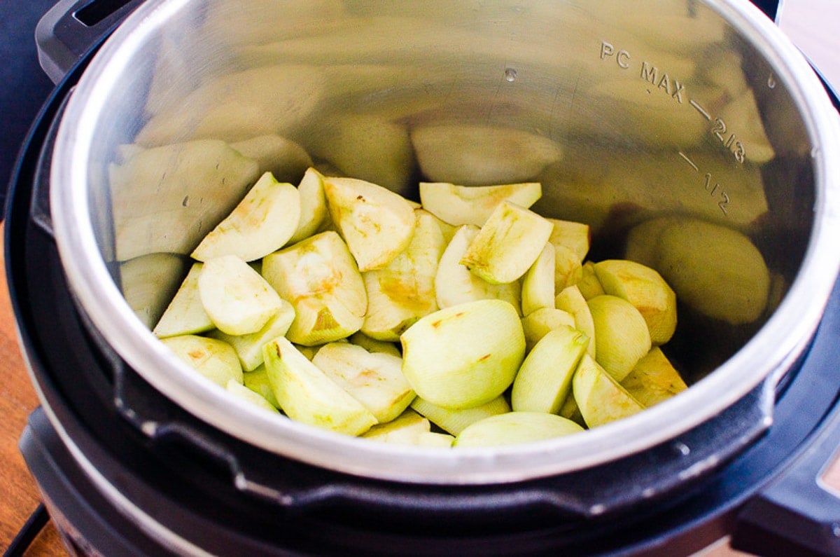 Cut apple pieces in pressure cooker pot.