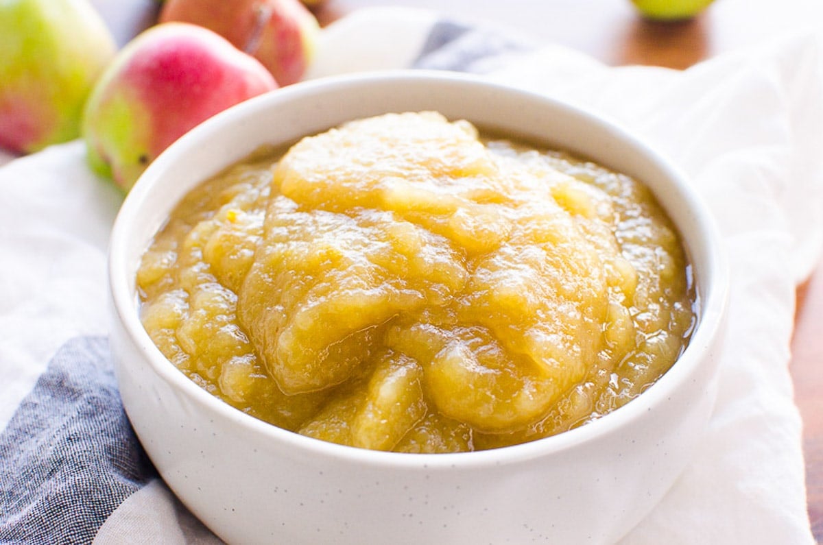Instant Pot applesauce in a bowl with fresh apples in background.