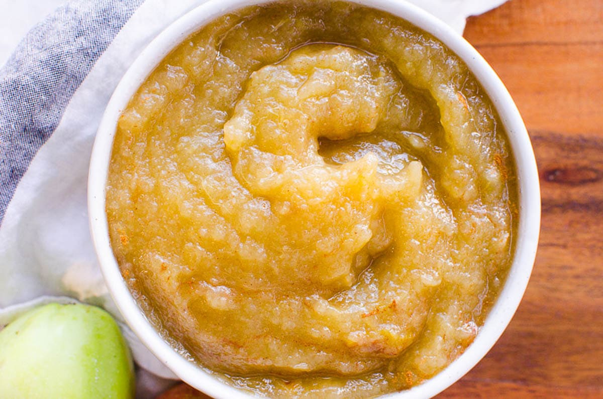 Homemade applesauce in a bowl with linen around it.