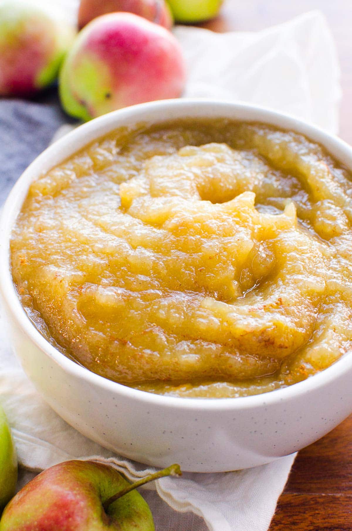 Instant Pot Applesauce in a bowl with fresh apples in background