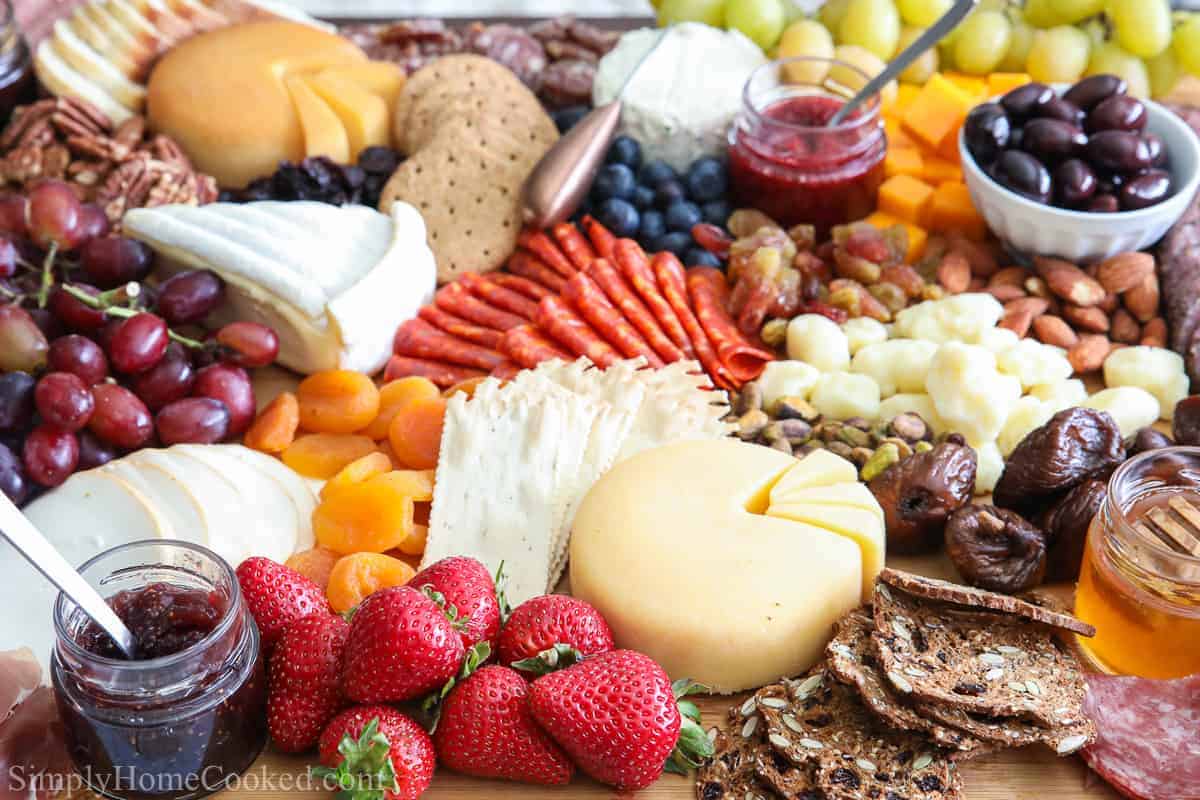 A variety of cheese, fruit, breads, meats on charcuterie board.