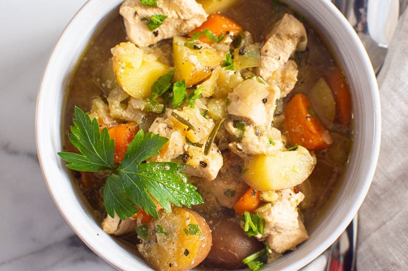chicken stew in a bowl with fresh parsley garnish