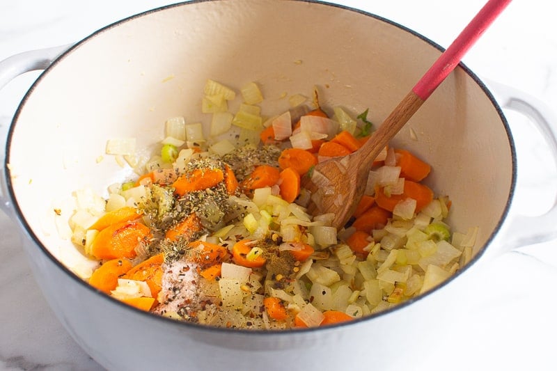 browning onion and vegetables with herbs in a pot