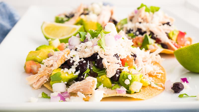 chicken tostadas on a white serving platter garnished with lime