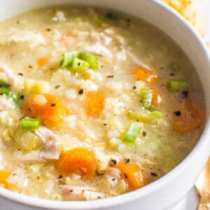 Instant Pot Chicken and Rice Soup with carrots, celery and green onion in white bowl.