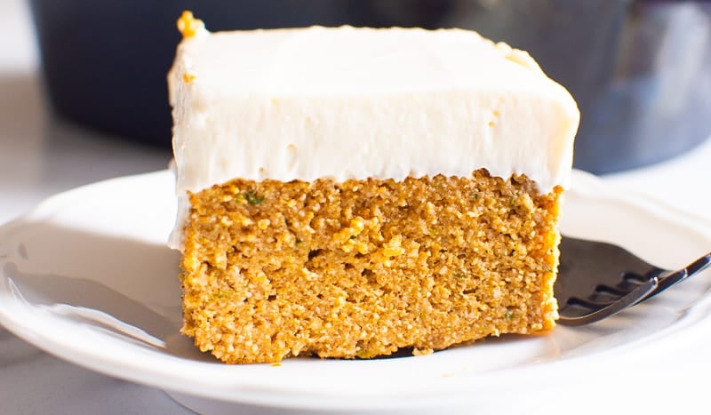 slice of healthy pumpkin cake with icing served on a white plate with fork