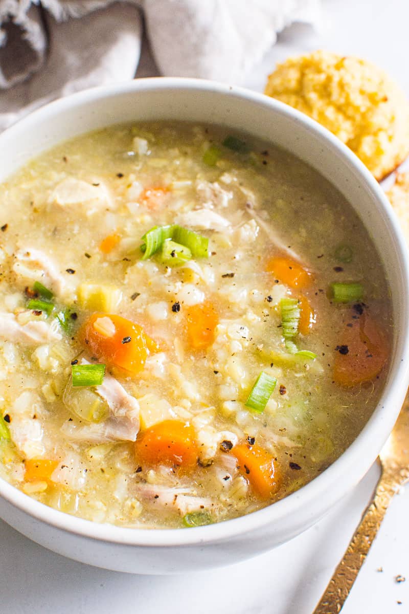 Instant Pot Chicken and Rice Soup with carrots, celery and green onion in white bowl.